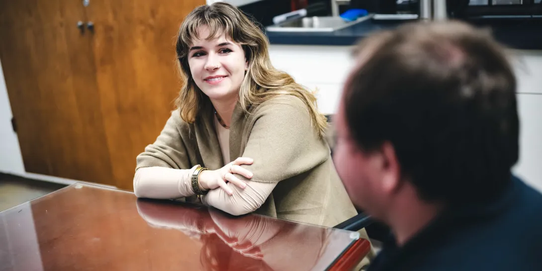 Female student and male student talking around a table.
